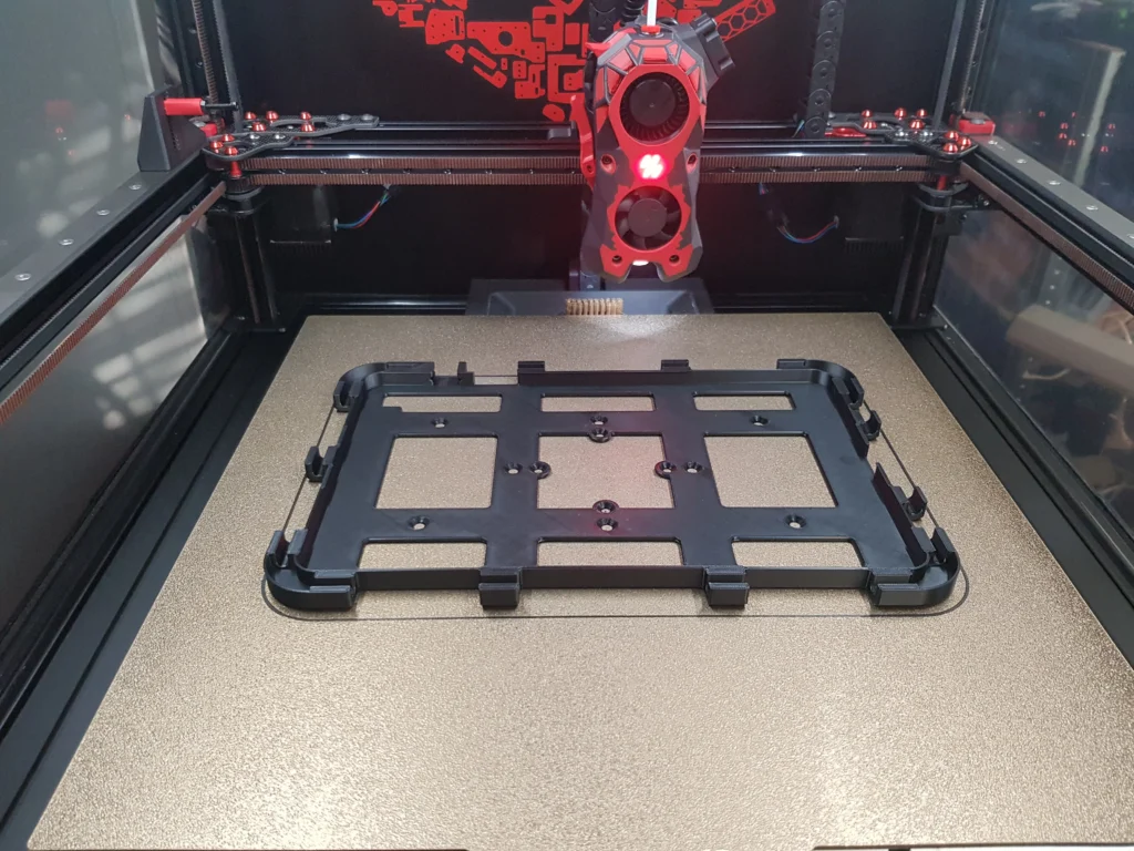 Inside the Voron 2.4 350: a freshly printed black frame on the textured build plate, the toolhead above it